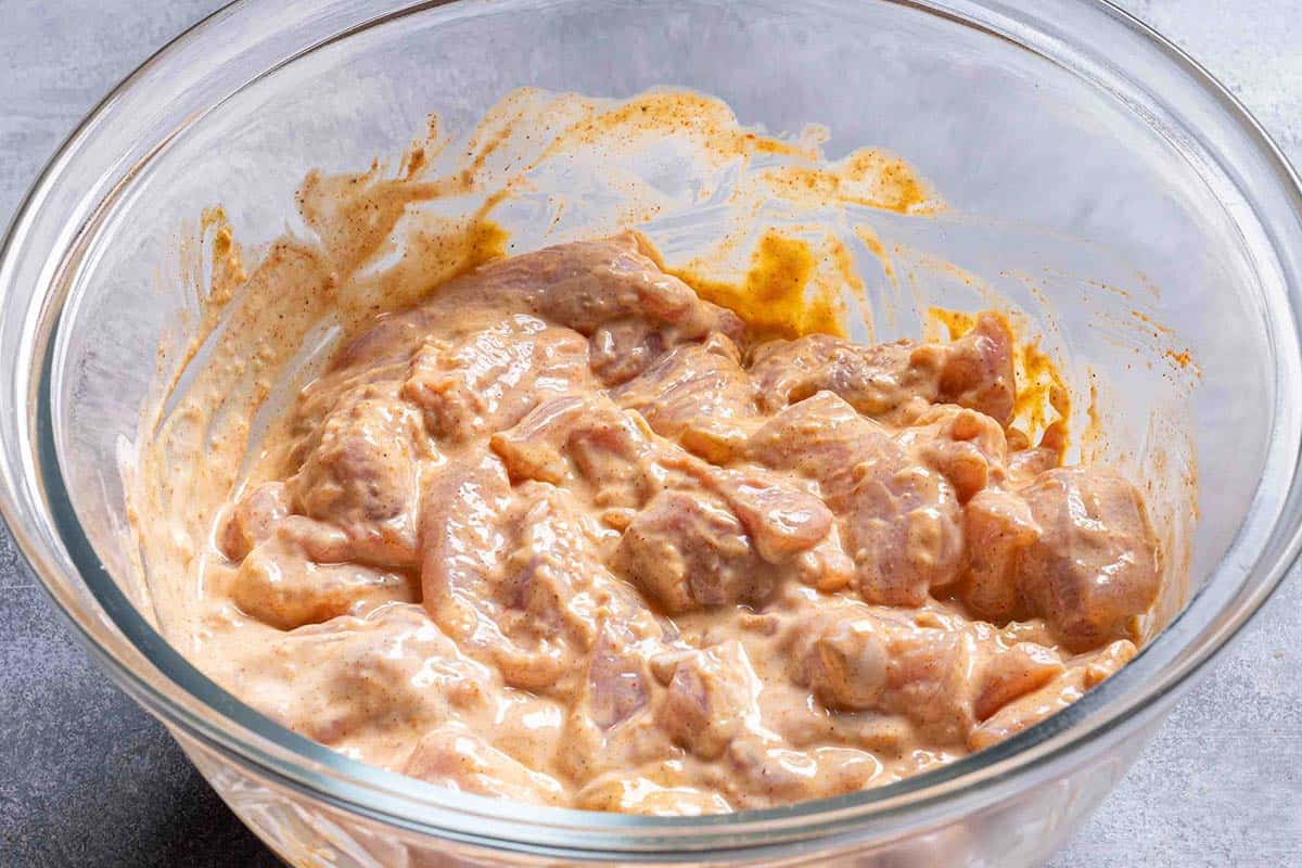 chicken thighs in a creamy marinade sitting in a glass bowl