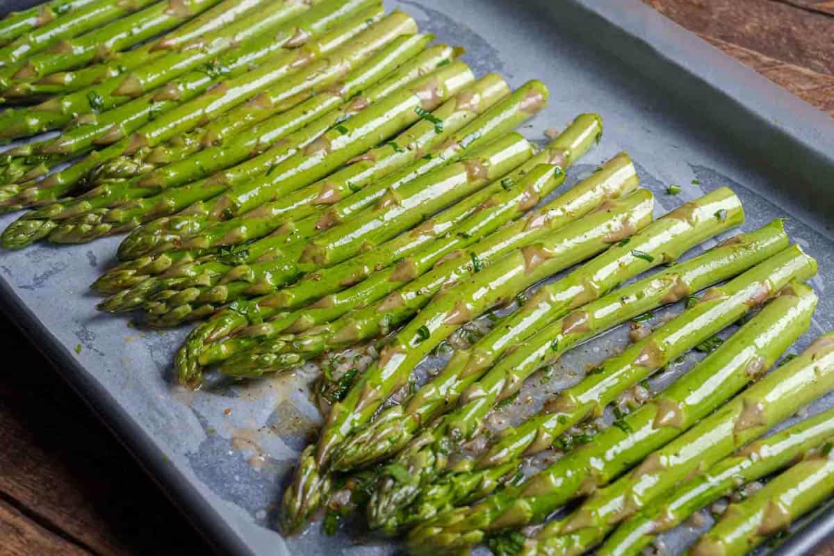 asparagi lined up in a single layer with space on a baking sheet.