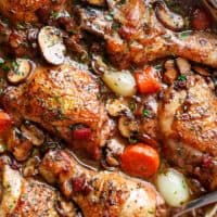 Coq Au Vin, or chicken in wine, is a popular classic French dish made easy in one pan! With crispy chicken drumsticks, chicken thighs and bacon, this Coq au vin gets everybody talking! Serve with creamy mashed potato or cauliflower smothered with butter, and the most delicious chicken dinner is ready on the table! | cafedelites.com