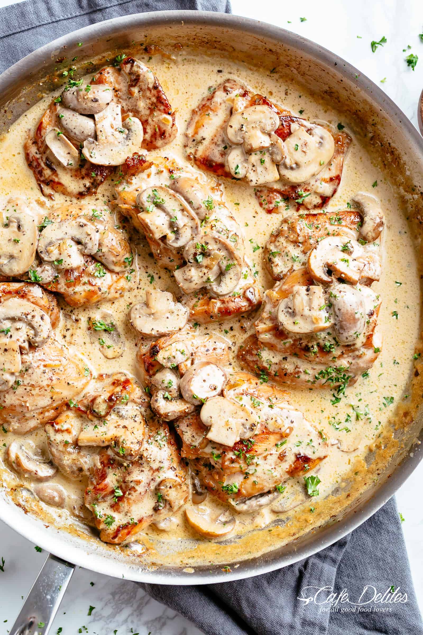 Crispy chicken thighs in a thick and creamy mushroom garlic sauce with a sprinkle of herbs and parmesan cheese is THE weeknight dinner everyone raves about! Serve over rice, pasta, mashed potatoes OR low carb Keto options like mashed cauliflower or zucchini noodles! | cafedelites.com