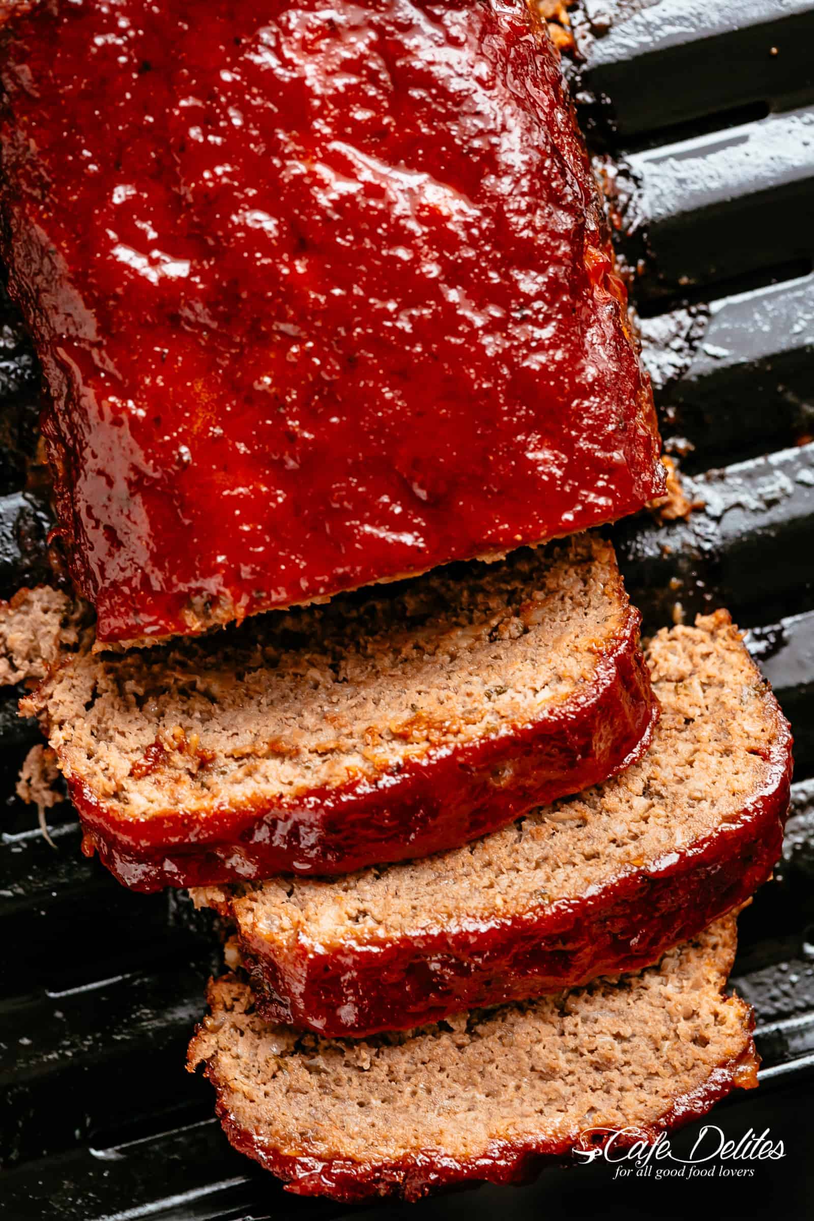 Bird's eye view of meatloaf on a grill, with three slices cut off the end. 