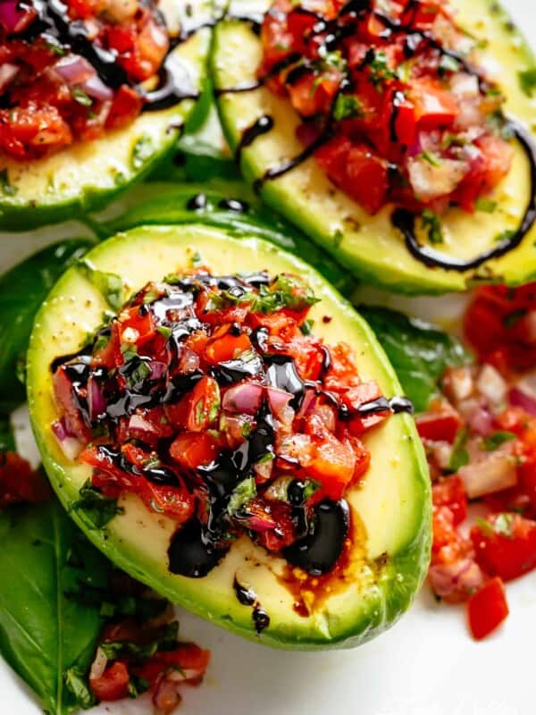 Bruschetta tomato stuffed into Avocados with parmesan and a balsamic reduction on a plate