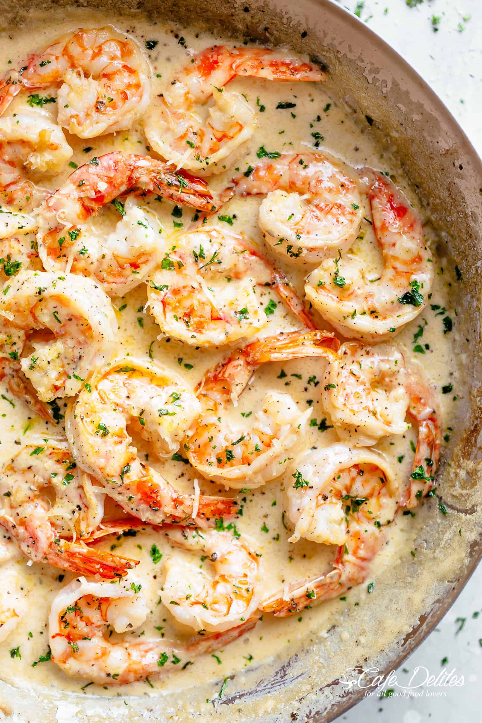 An image of half a silver pan filled with creamy shrimp garnished with fresh chopped parsley! Pan sites on a light grey board | cafedelites.com
