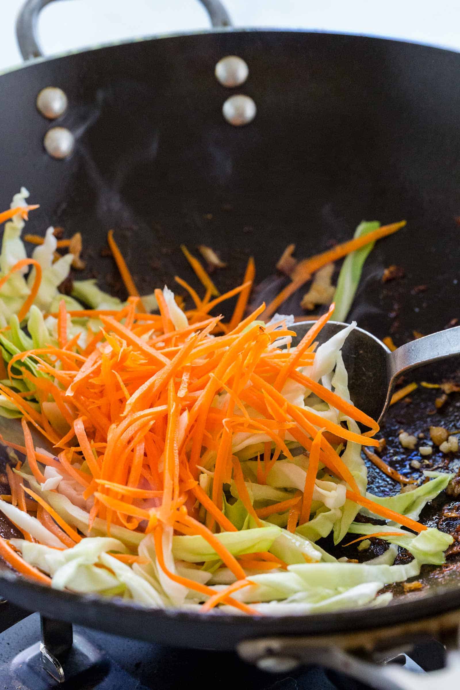 stir frying sliced carrots and cabbage in a wok