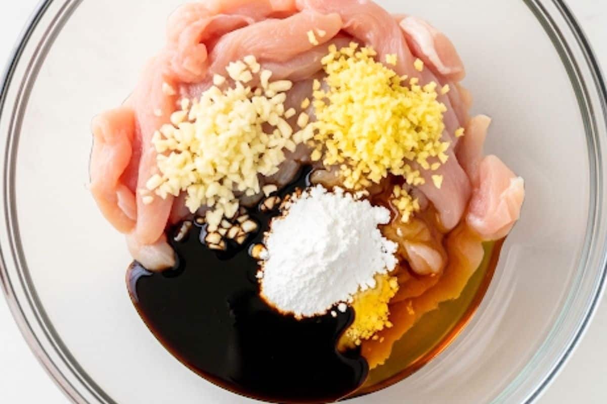 In a bowl, combine sliced chicken, garlic, ginger, soy sauce, cornstarch and sesame oil.