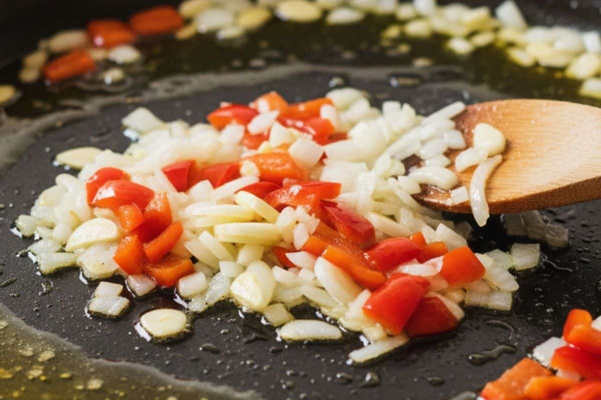 Add the onion, garlic, and diced red capsicum and cook in a paella pan.
