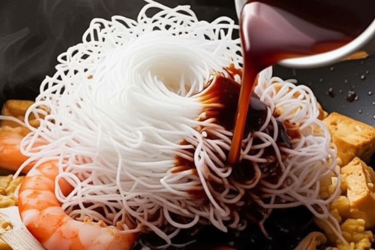 add the rice noodles in the pan and pour the pad thai sauce 