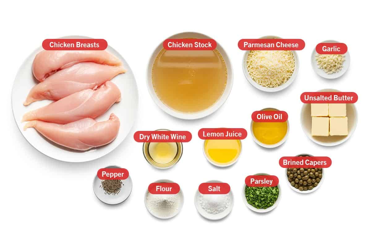 Top shot of ingredients: Chicken breasts, chicken stock, parmesan cheese, garlic, dry white wine, lemon juice, olive oil, unsalted butter, pepper, flour, salt, parsley, and brined capers.