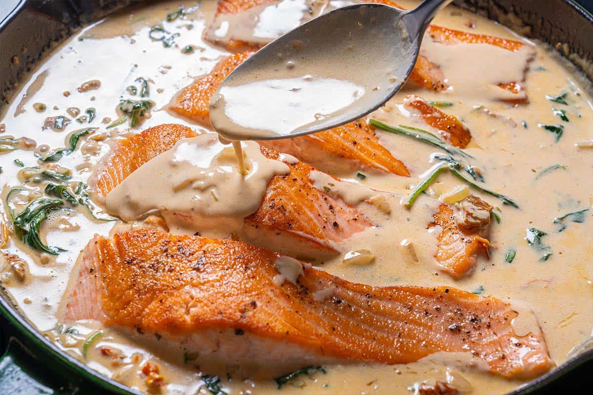 Salmon fillets are being returned to the sauce to absorb its flavors.