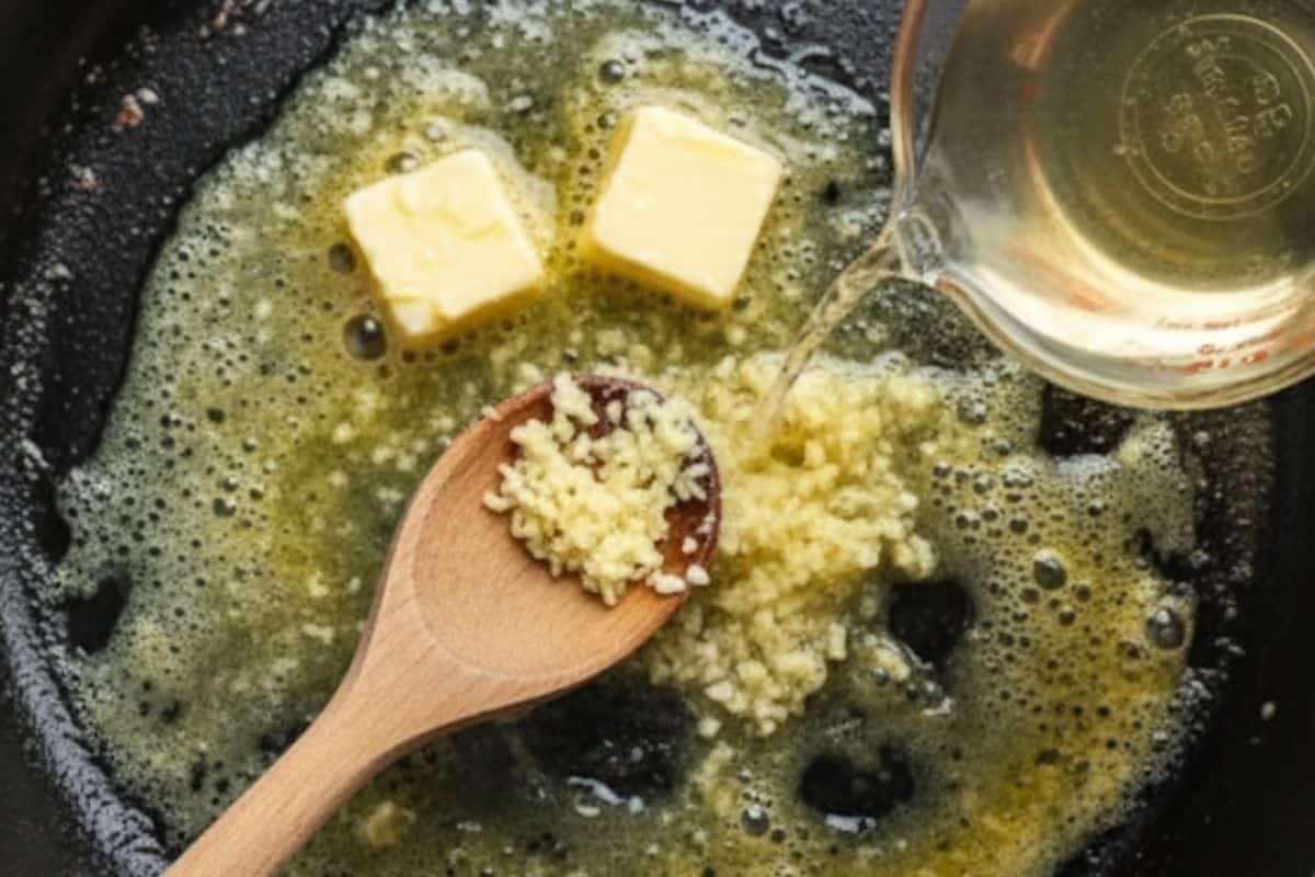 Add the remaining butter to the skillet and sauté garlic for 1 minute until fragrant. Pour in white wine or broth and simmer to reduce by half.