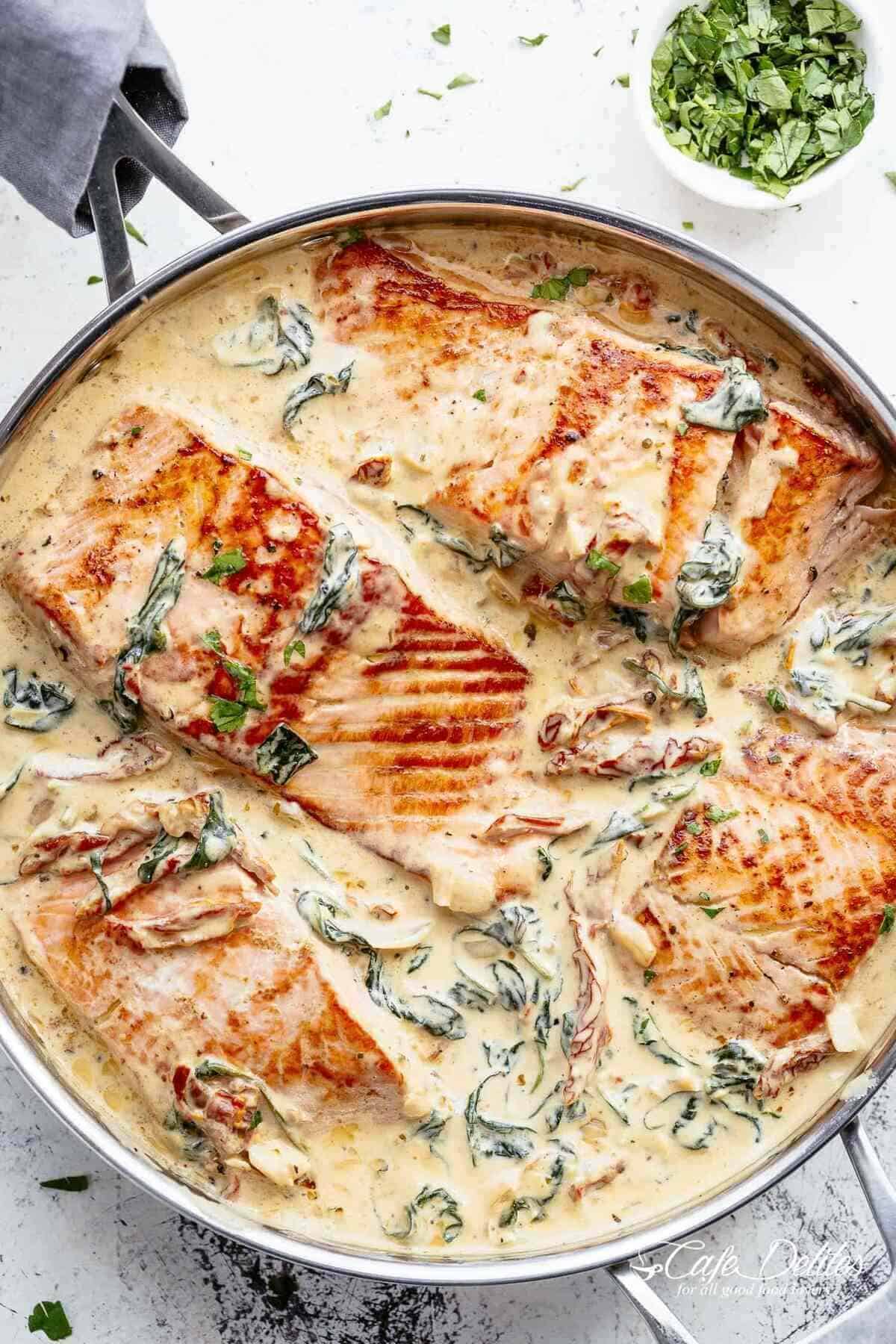 Close-up image of creamy garlic butter Tuscan salmon in a pot.