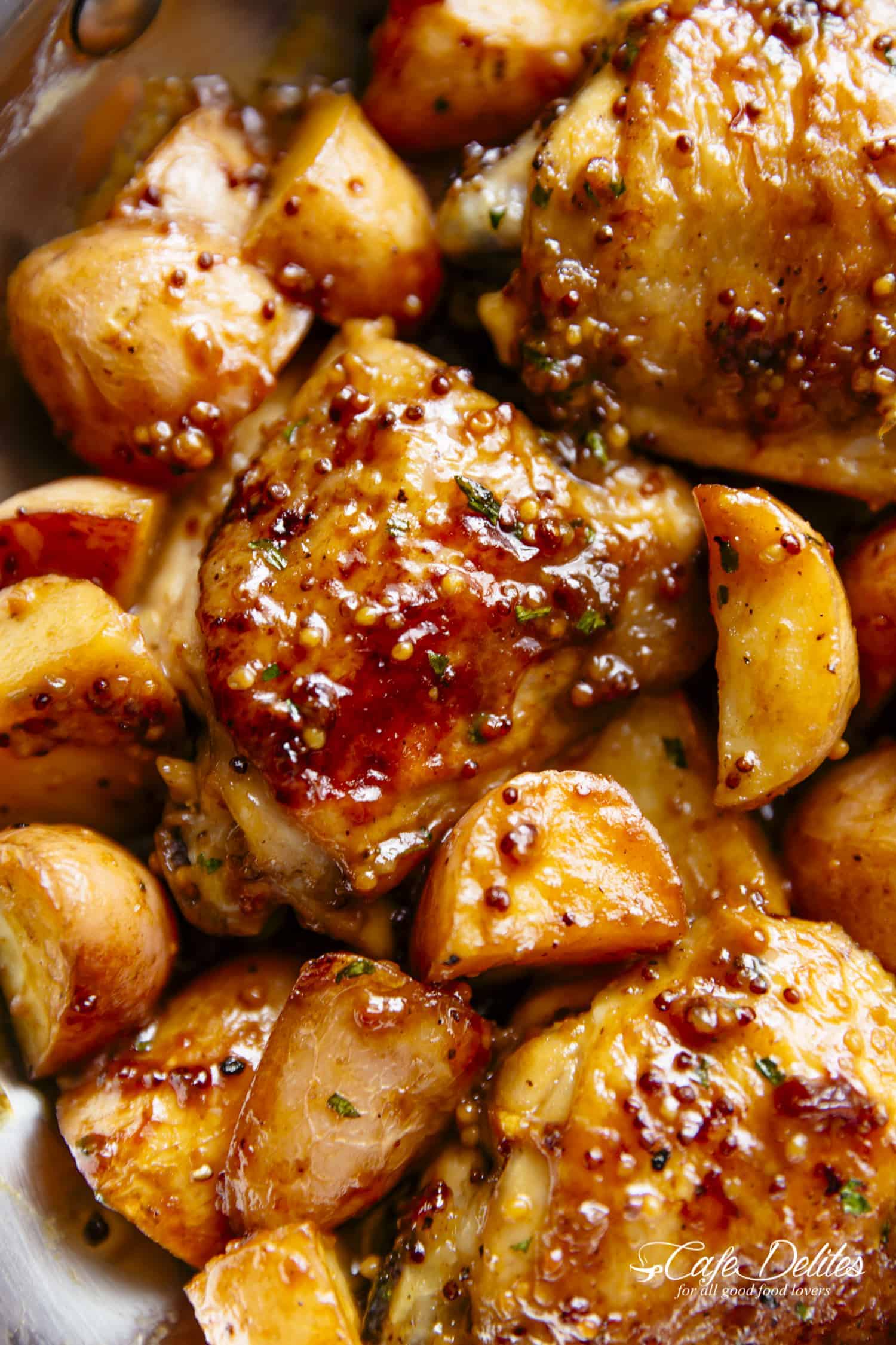 Close up of chicken thigh on bed of potatoes covered in sauce. 