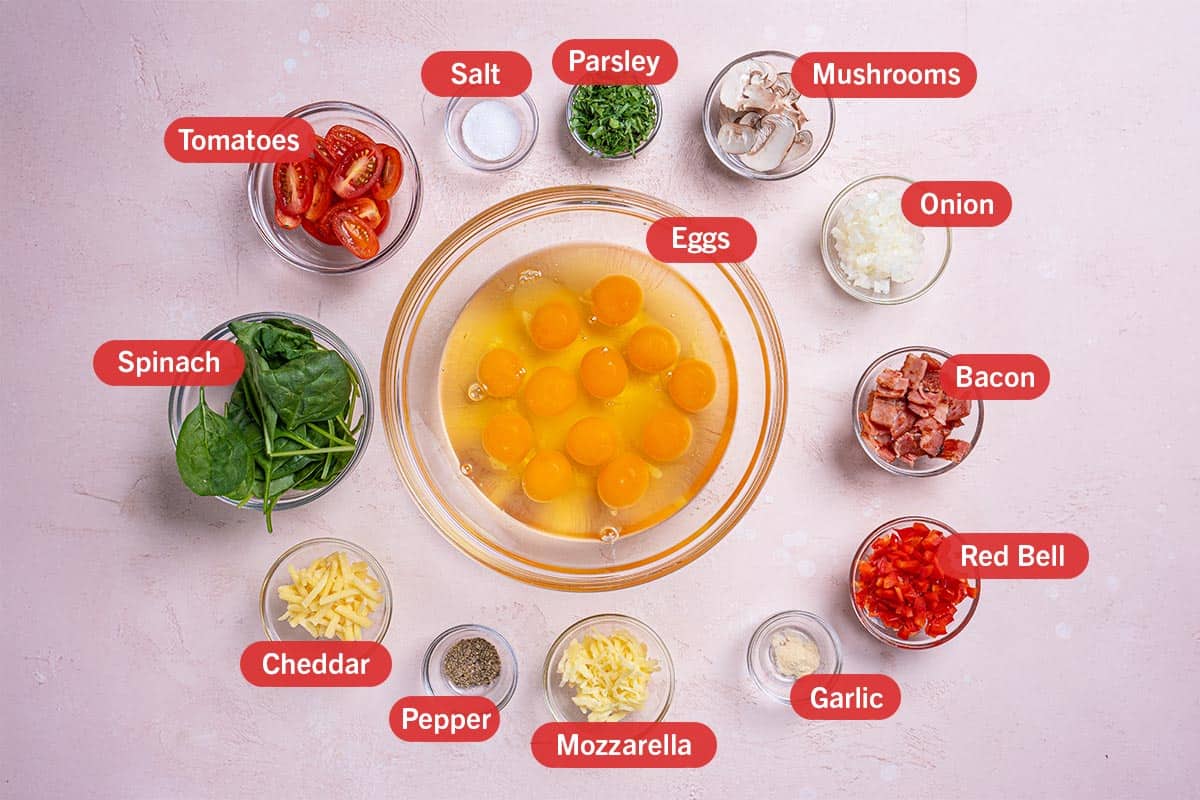 Image of all the ingredients needed for the preparation of this recipe, specifically: eggs, salt, parsley, mushrooms, onion, bacon, red bell, garlic, mozzarella, pepper, cheddar, spinach, tomatoes.