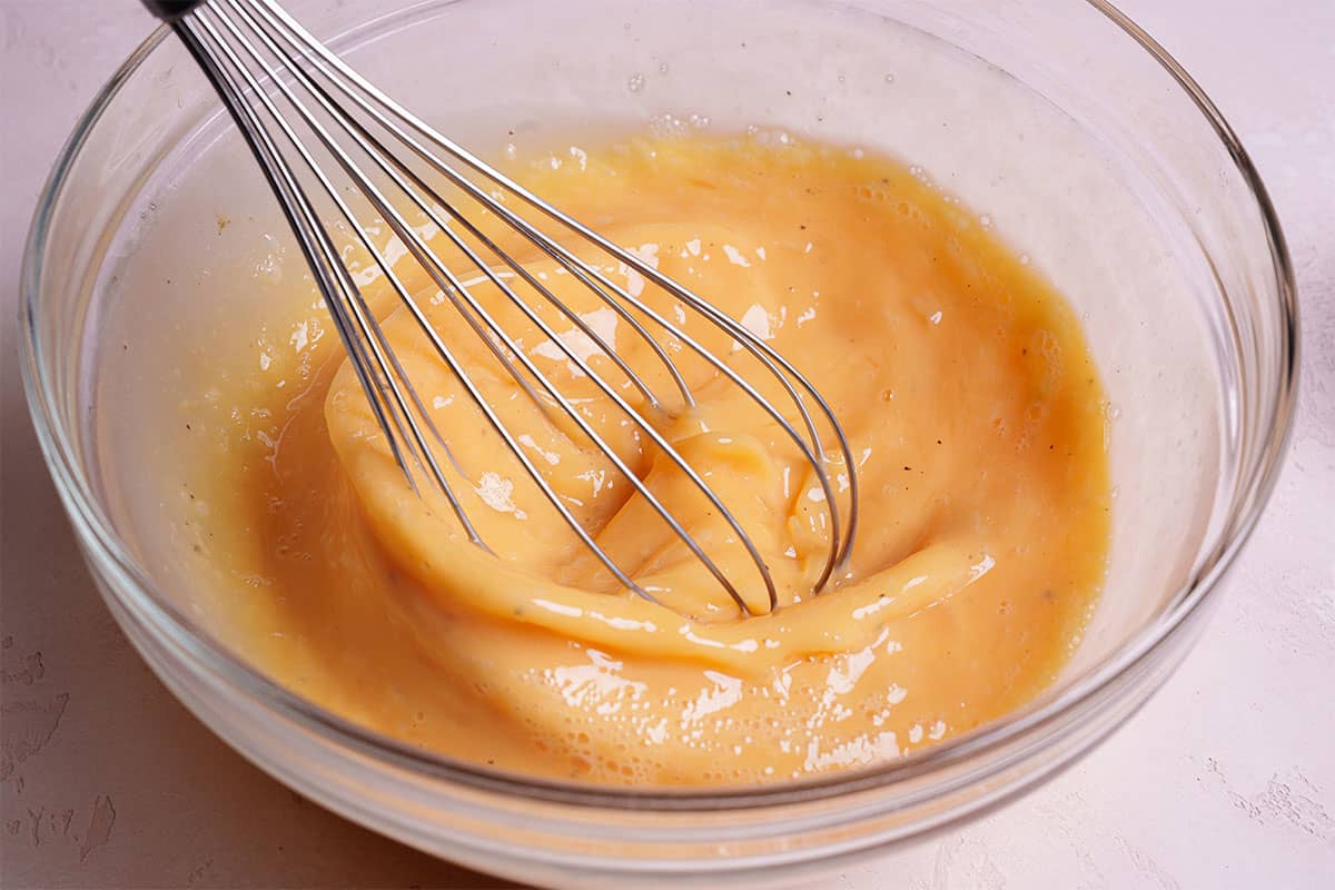 An image of eggs being whisked together in a clear bowl.