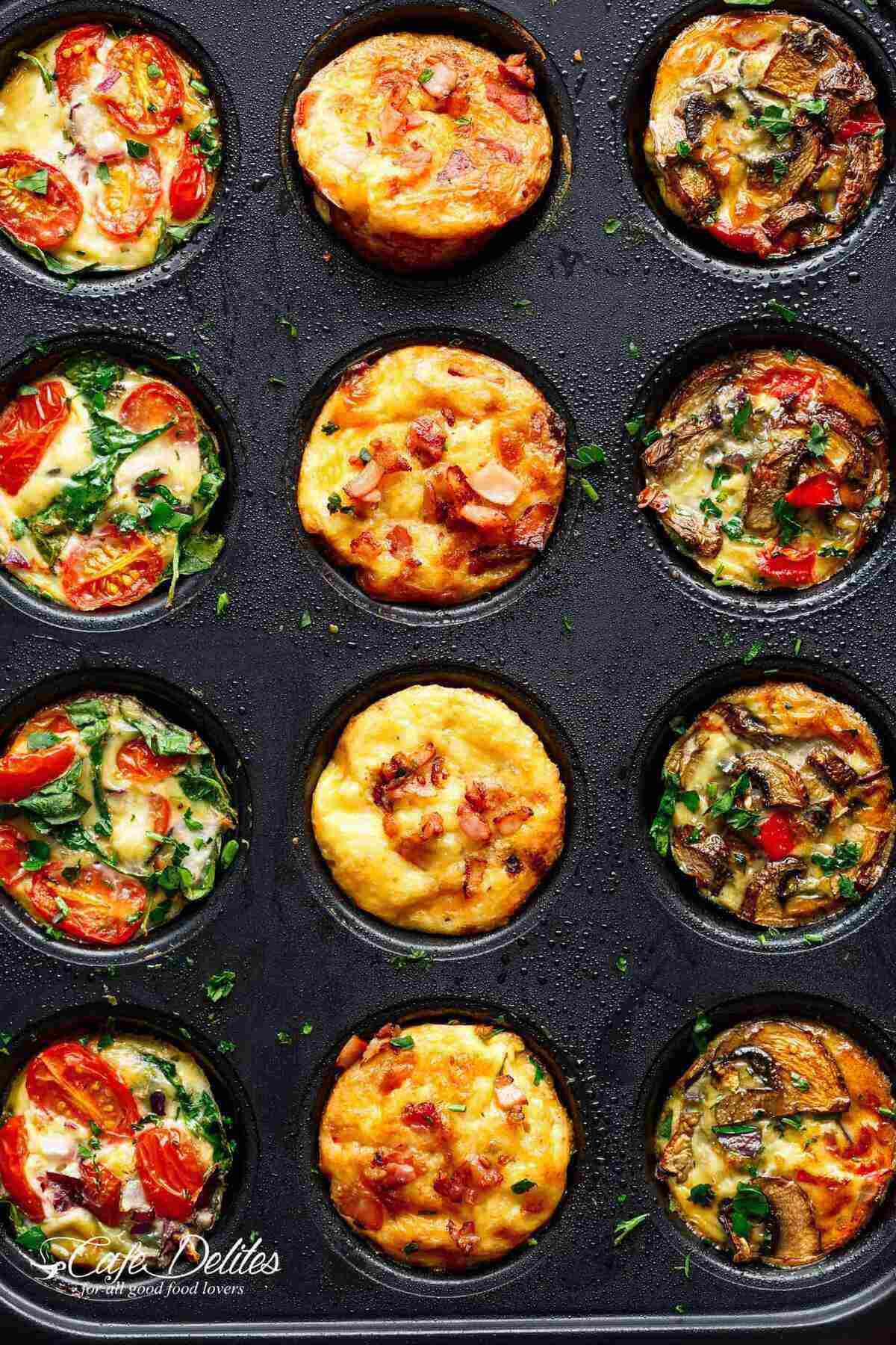 A muffin tray showcasing three rows of breakfast muffins: one row with spinach, tomato, and cheese; another with egg and cheese muffins topped with bacon; and the third with tomatoes, mushrooms, and green herbs.