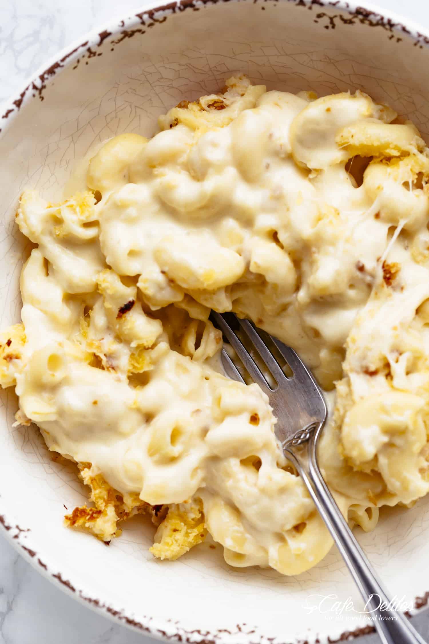 Mac And Cheese is better than the original! A creamy garlic parmesan cheese sauce coats your macaroni, topped with parmesan fried bread crumbs, while saving some calories! | https://cafedelites.com