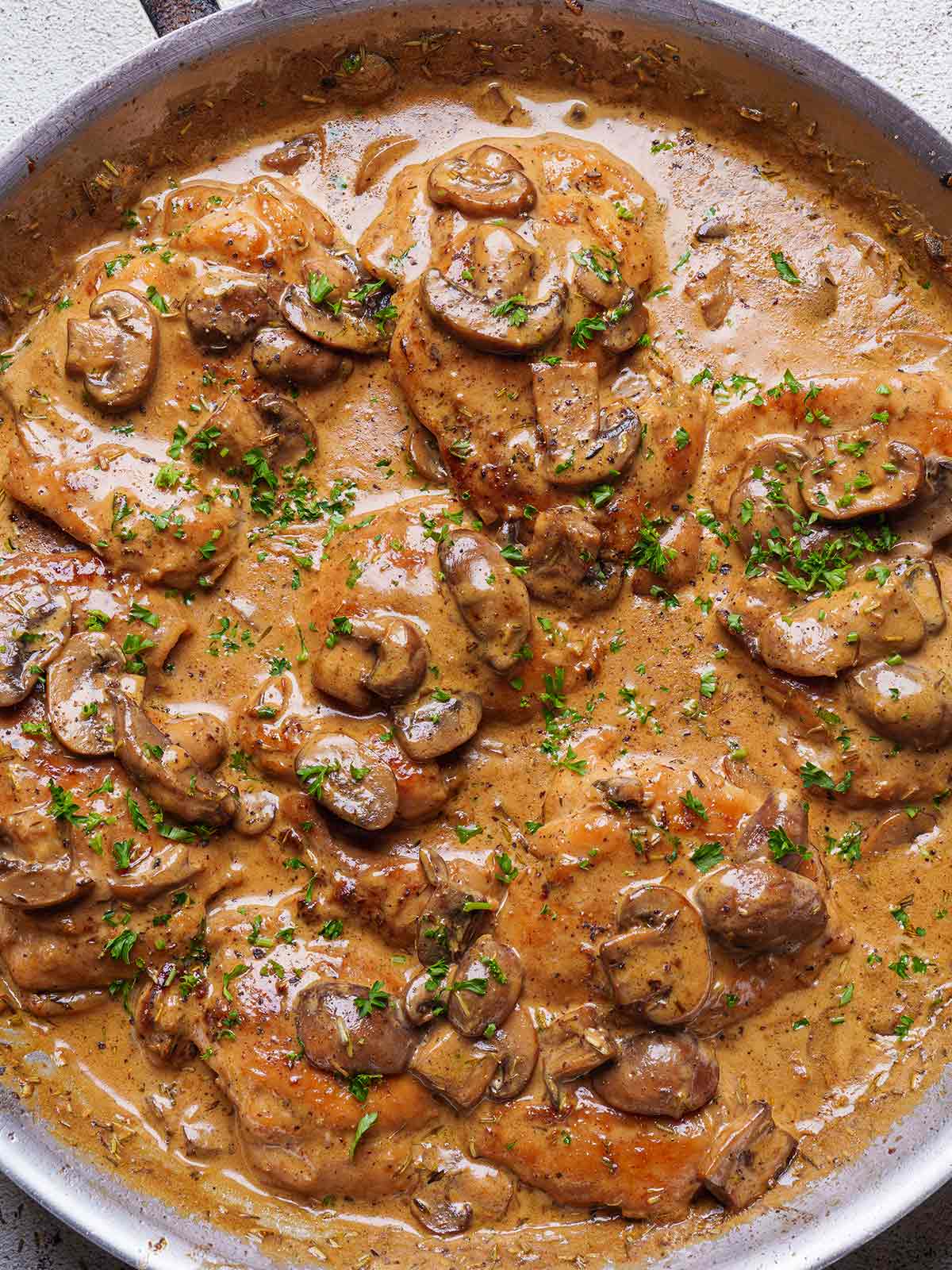 Chicken Thighs With Creamy Mushroom Sauce garnished with parsley in a pan