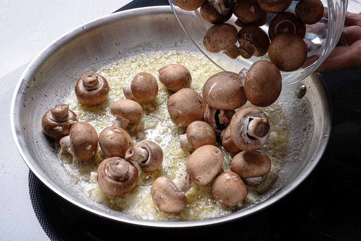 An image shows onions being added to a pan containing oil and butter that are frying.