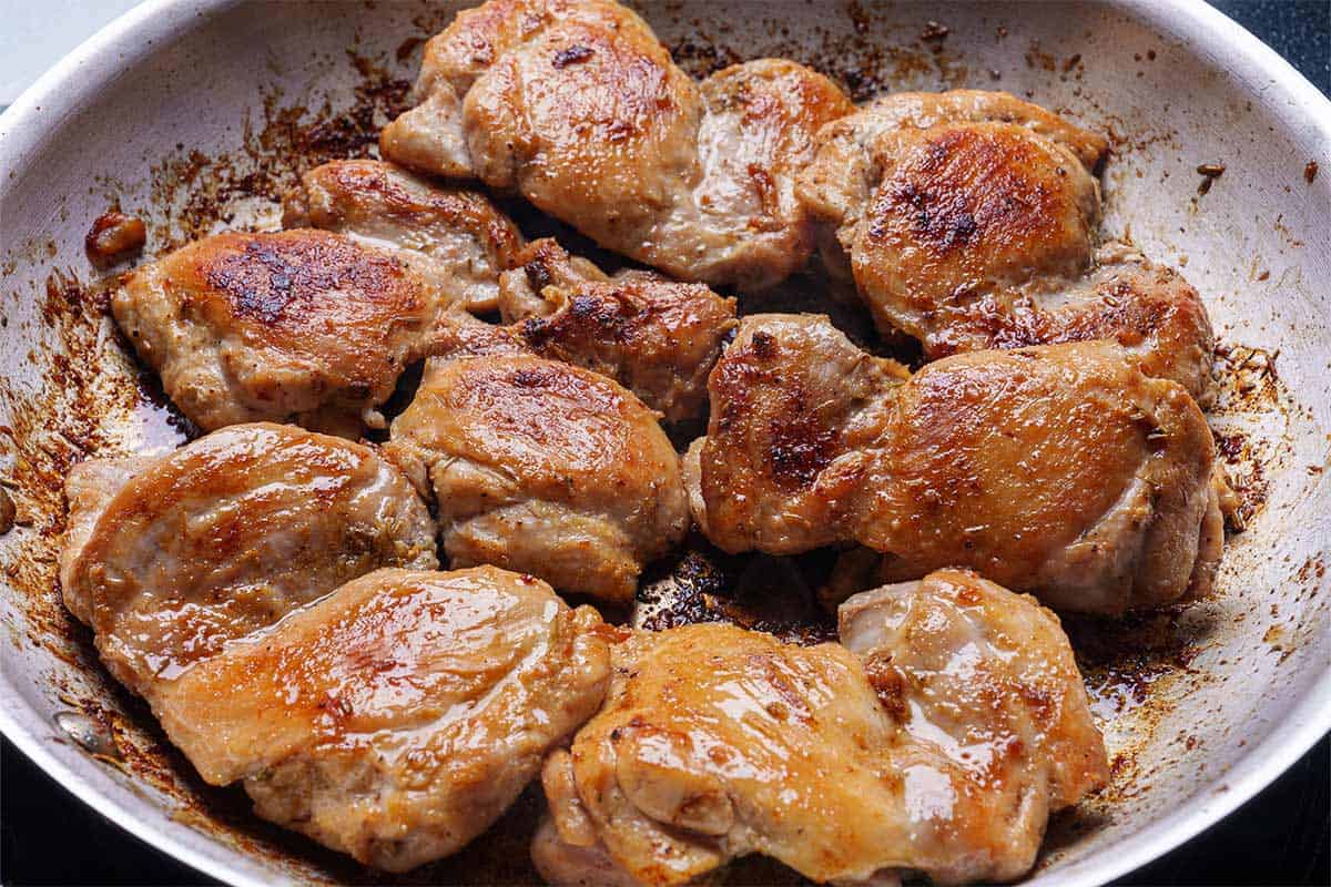 chicken seared in the pan light browned and coated in seasoning 