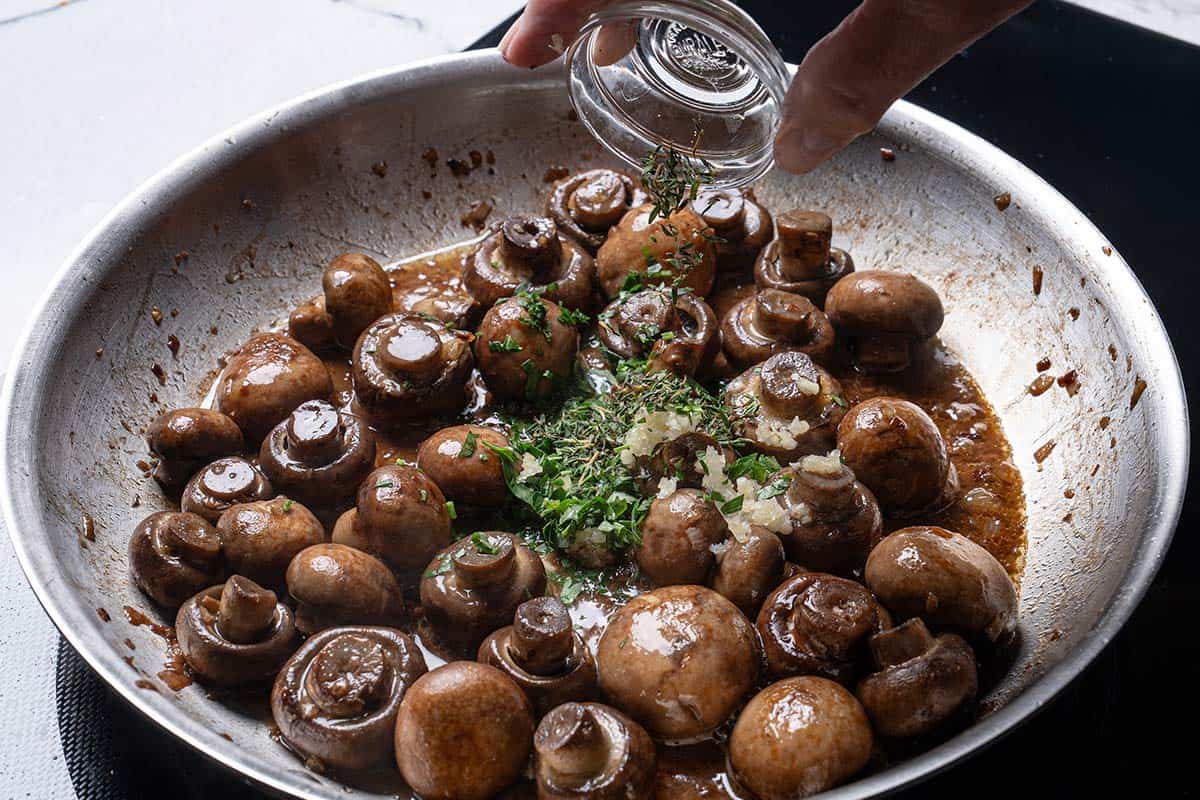 Image of herbs being added to the pan.