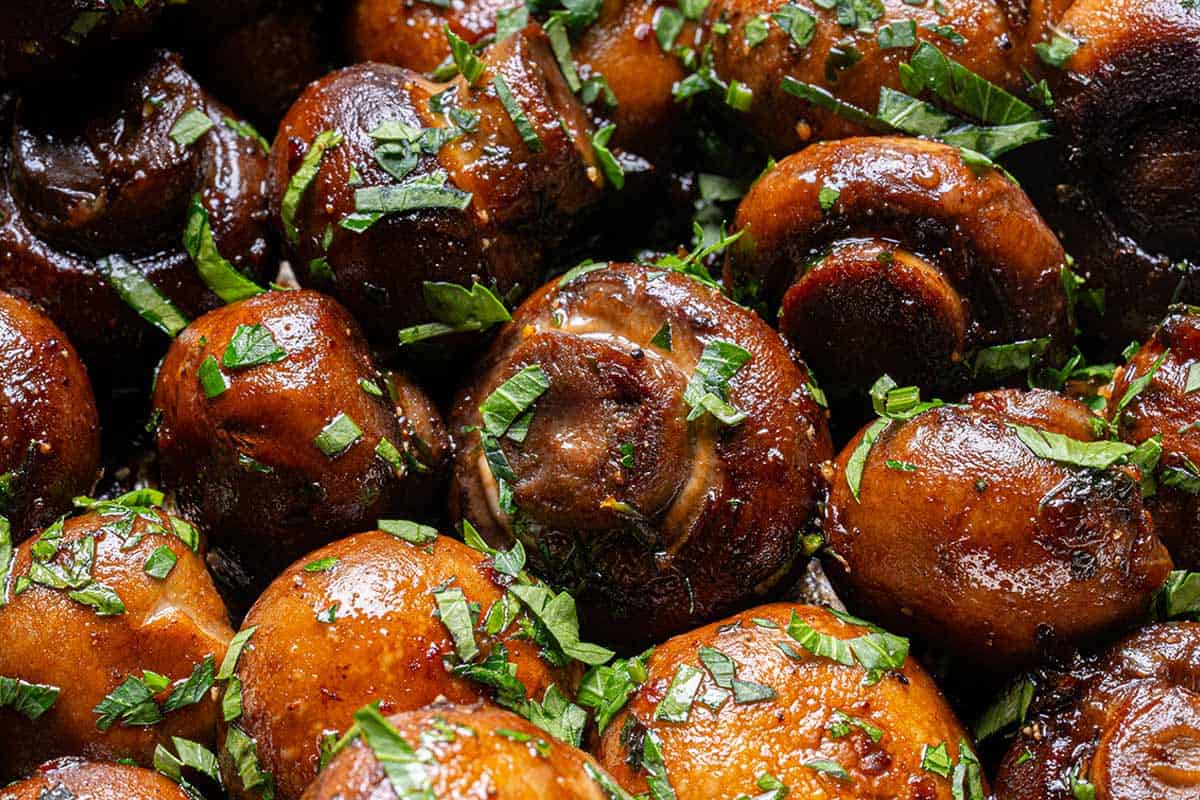 Close up image of buttery garlic mushrooms coated in parsley.