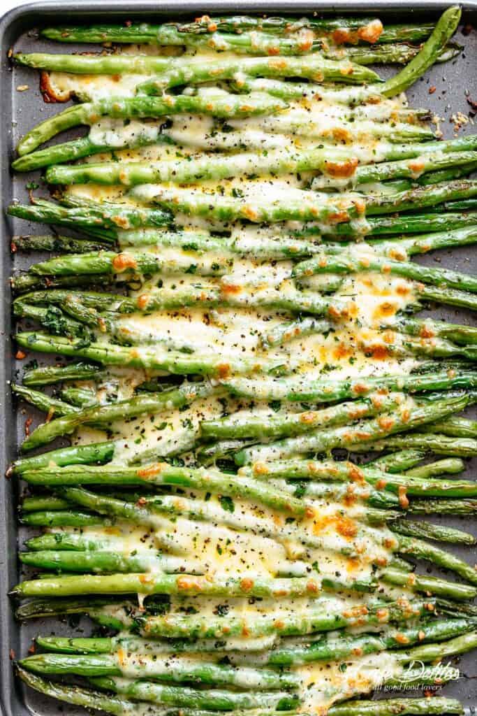 A tray full of roasted green beans with melted cheese