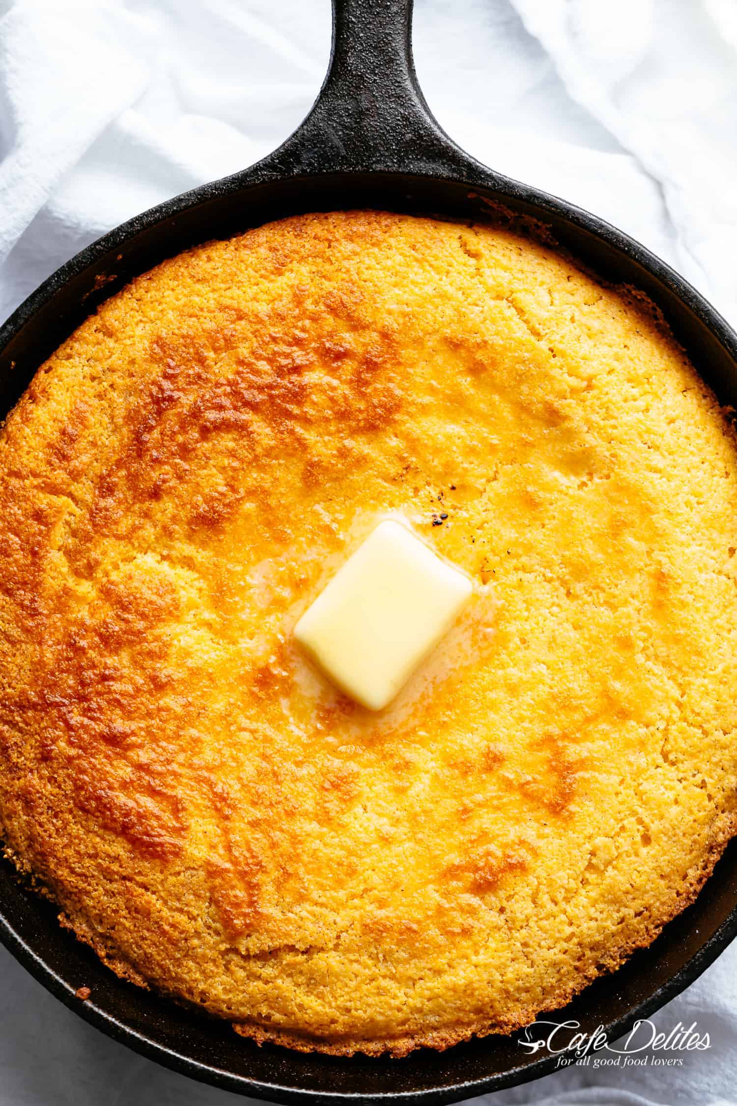 Moist cornbread in a skillet with butter