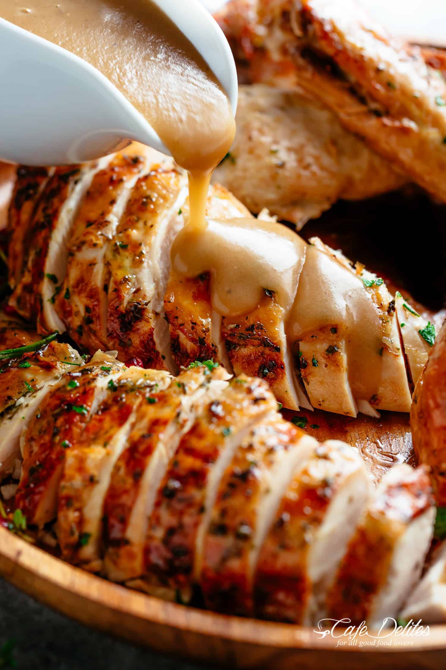 close up of gravy being poured on cooked turkey