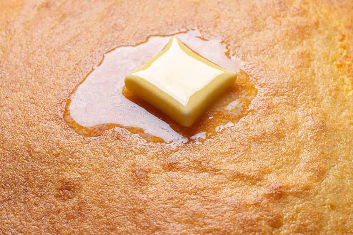 A close-up picture of the finished cornbread, with a small square of butter melting on top.