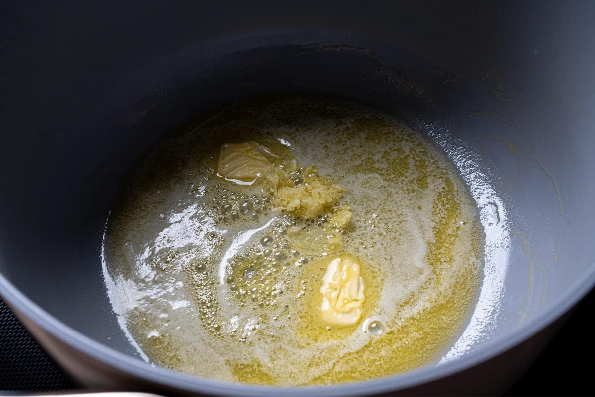 An image of butter being sautéed in a pan with the addition of garlic.