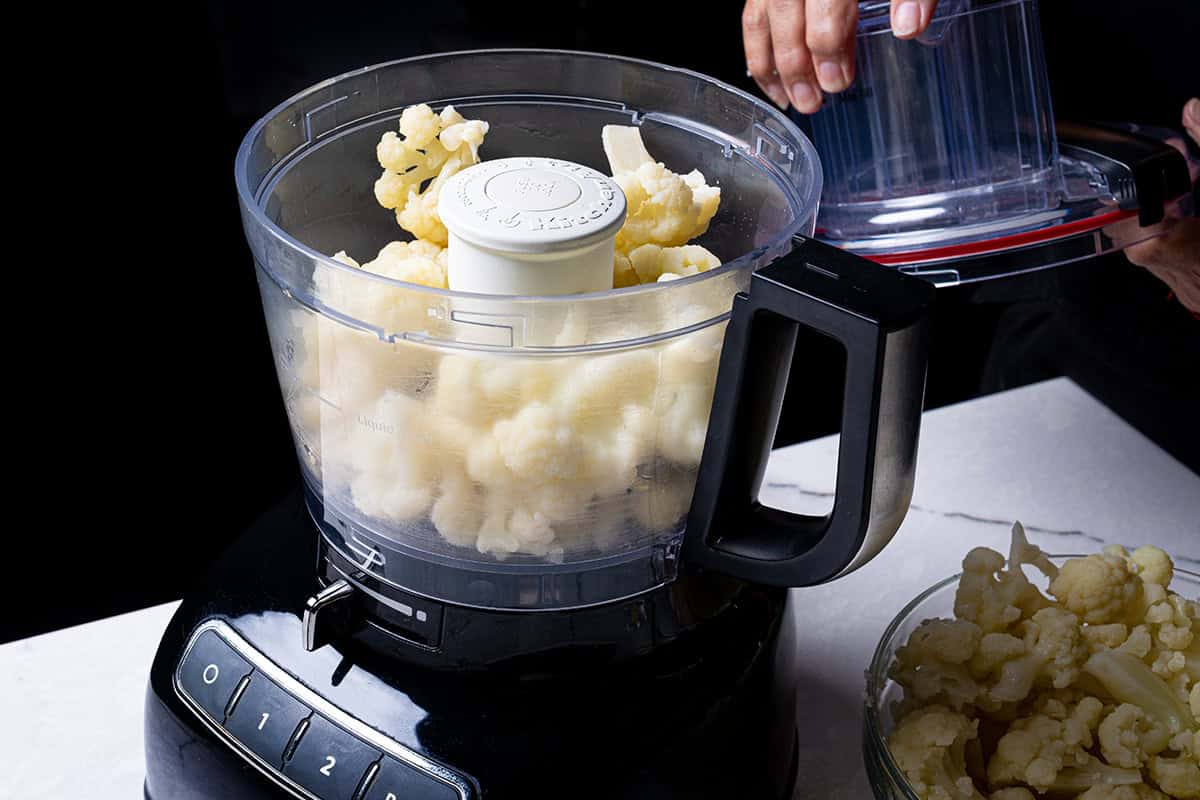 An image of the cauliflower being blended in a food processor until smooth.