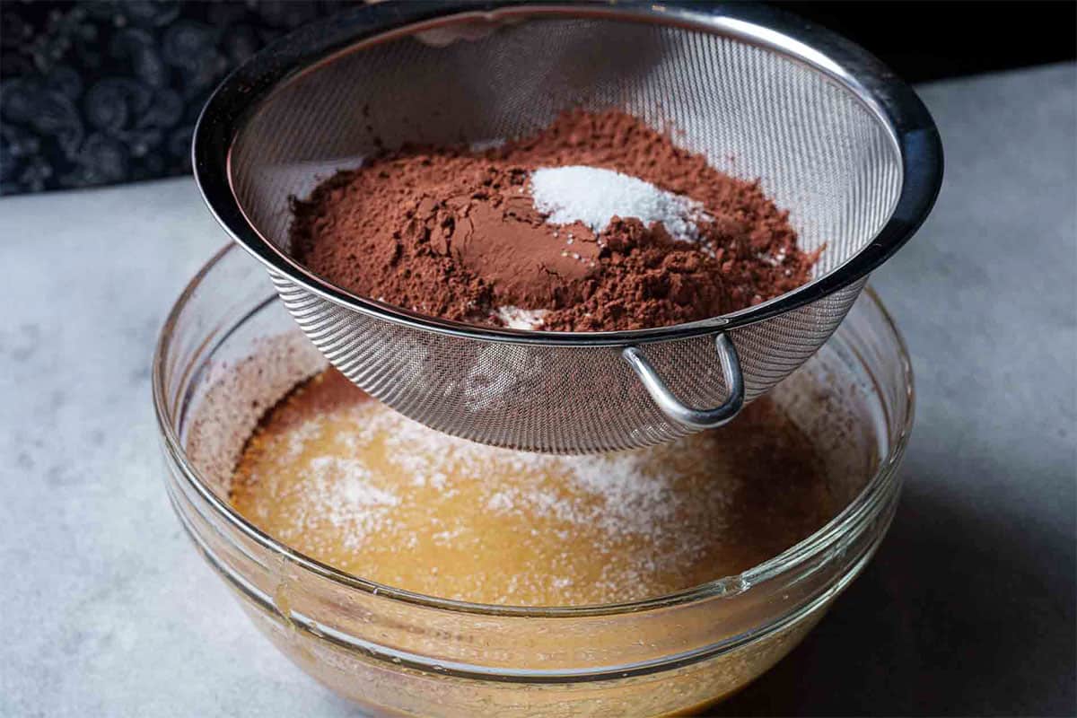 Cocoa and butter being added to the mix of ingredients previously whisked together.