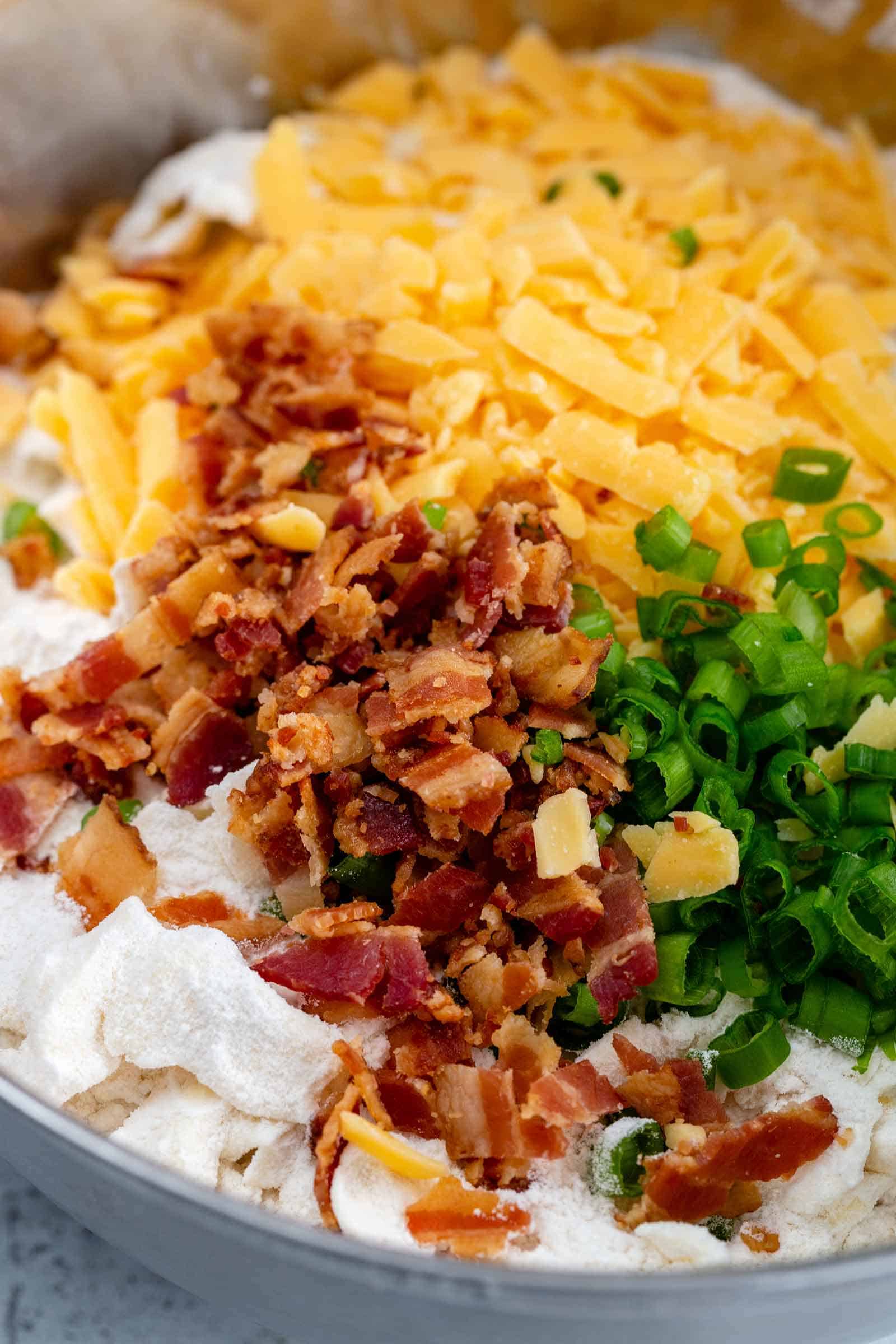 chopped bacon, grated cheddar cheese and sliced green onions in a mixing bowl