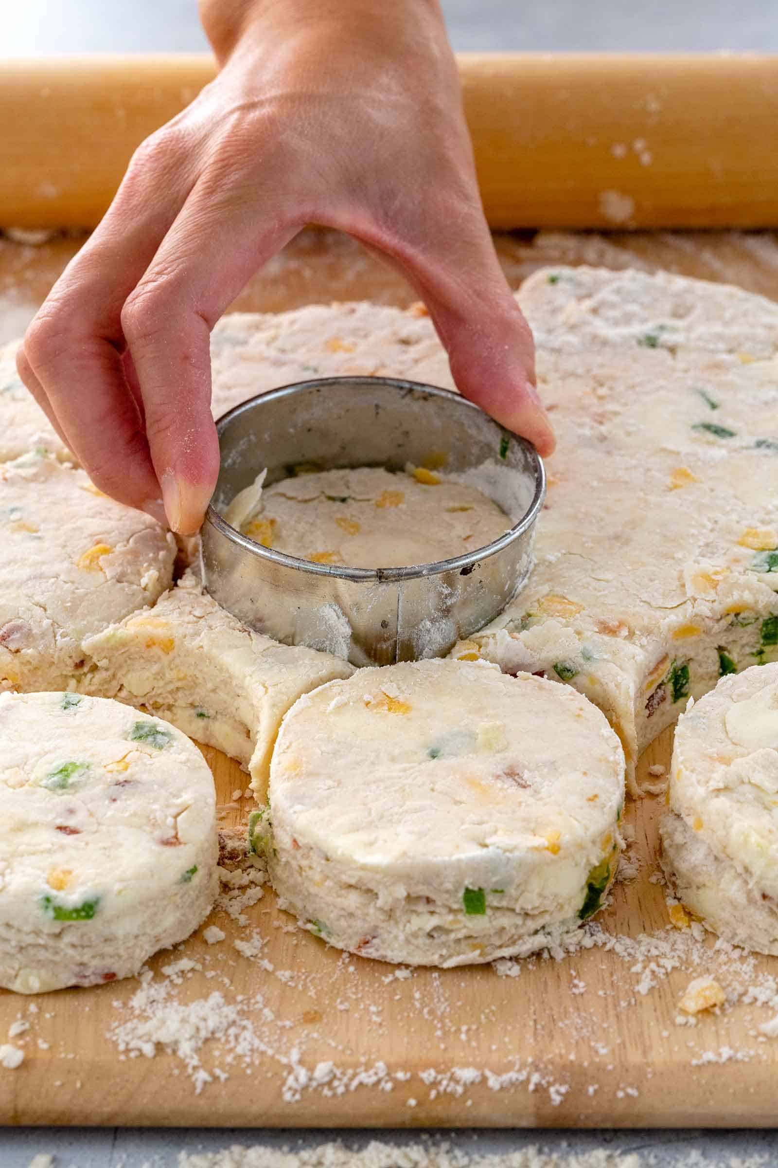 hand pressing round biscuit cutter into dough