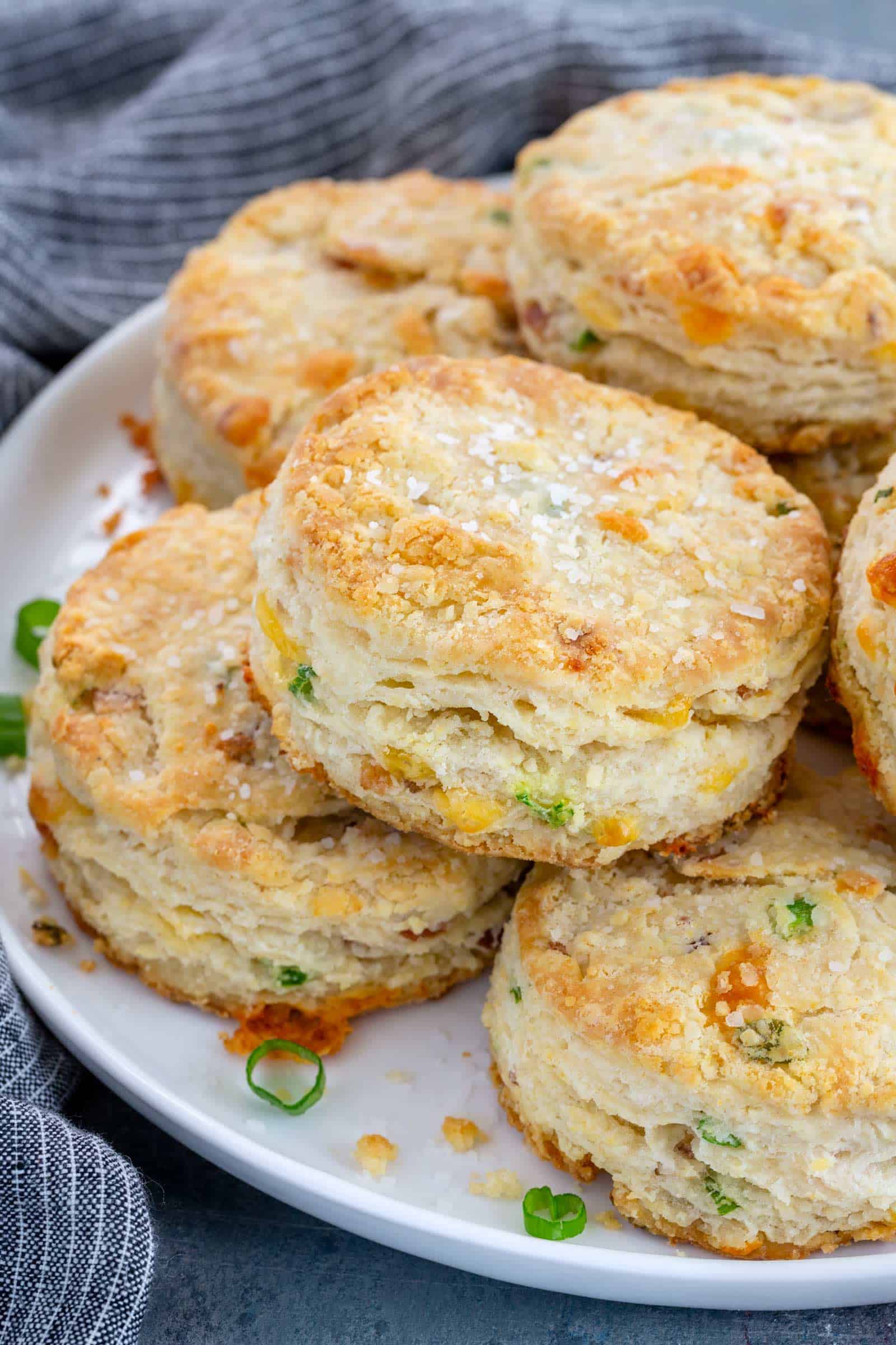 bacon cheddar biscuits stacked on a white plate