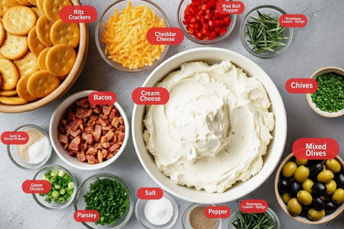 Flat lay of ingredient shot of ritz crackers, cheddar cheese, red belll peppers, rosemary leavess sprigs, chives, mixed olives, pepper, salt, parsley. green onions, bacon, garlic and onion powder.