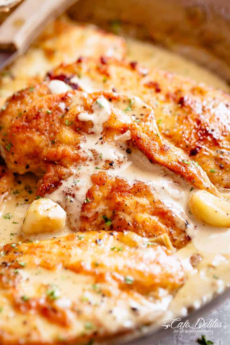 Three chicken breasts with a crispy golden outer coating in a mouth-watering garlic cream sauce with whole garlic cloves. | cafedelites.com