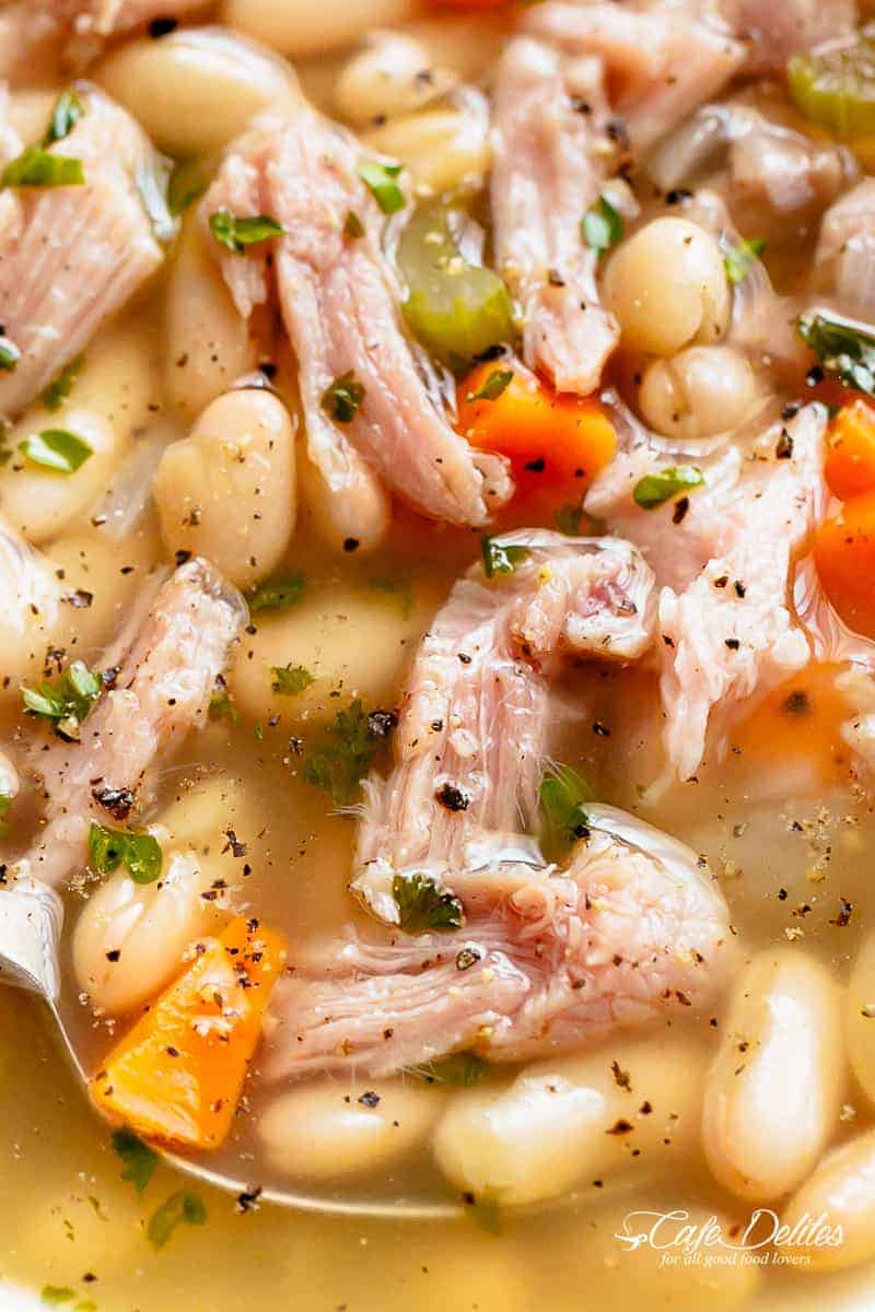 Close-up top view of ham and bean soup, showcasing chunks of ham, beans, and diced carrots.