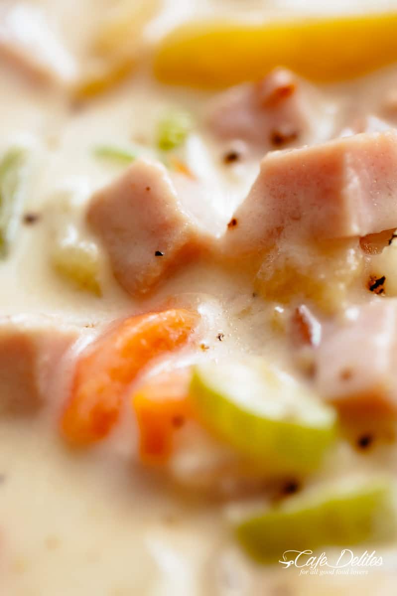 Close up of pieces of cooked ham, carrot and celery in the soup. 