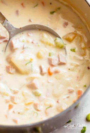 Creamy Ham And Potato Soup in a bowl being scooped up by a spoon before being eaten