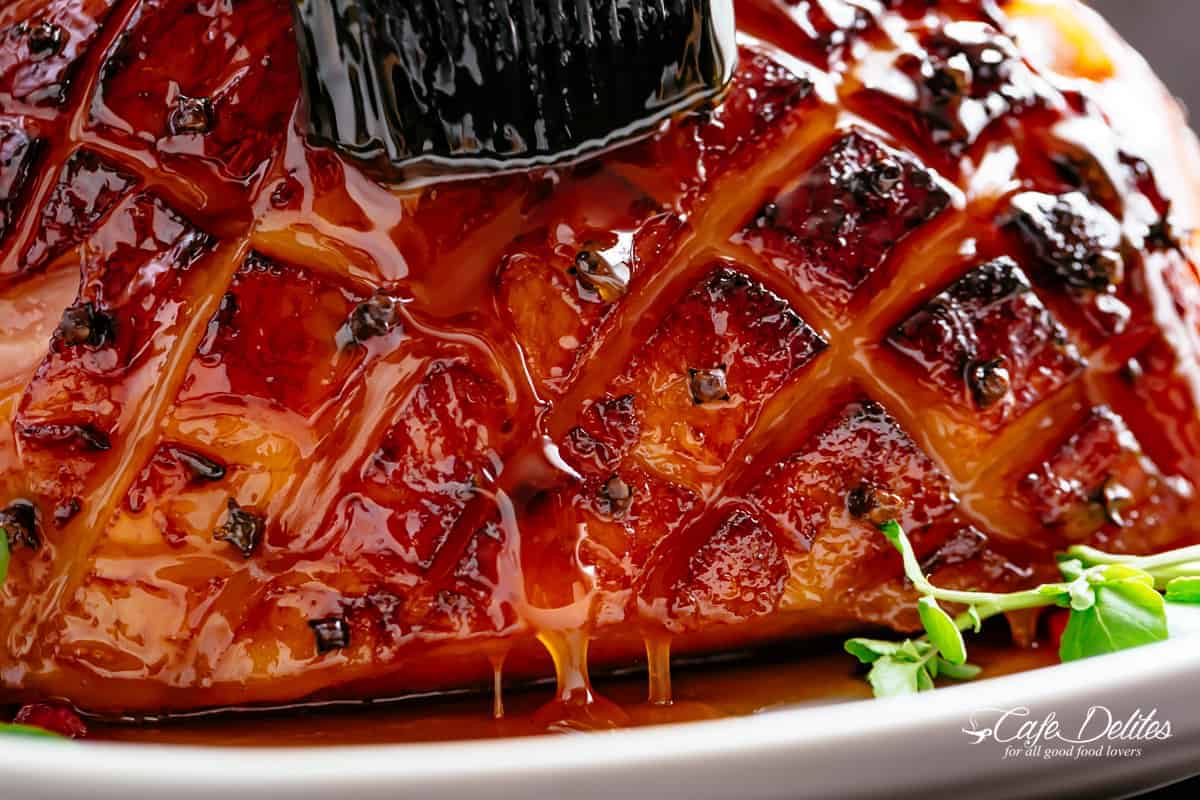 honey glazing ham on plate with a black brush