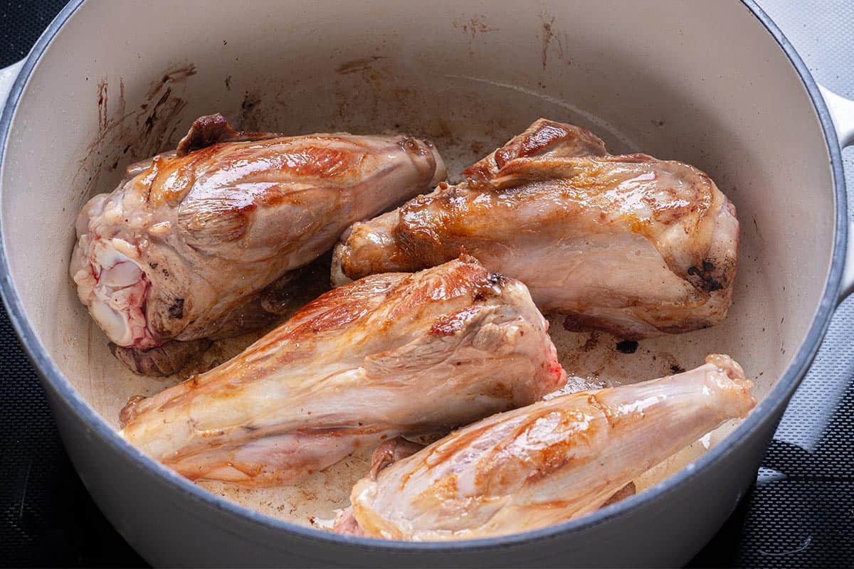 lamb shanks seared in a blue pot