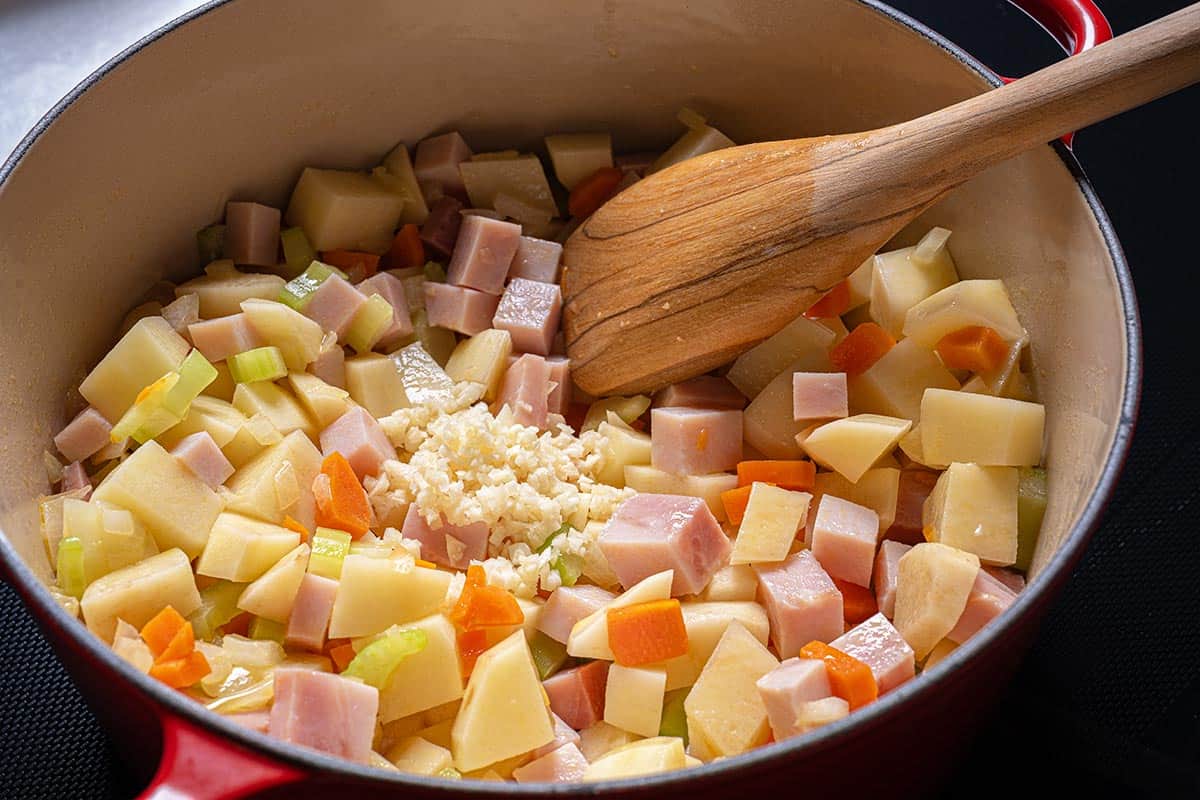 Image of ham, garlic, and potatoes being added to the soffritto.