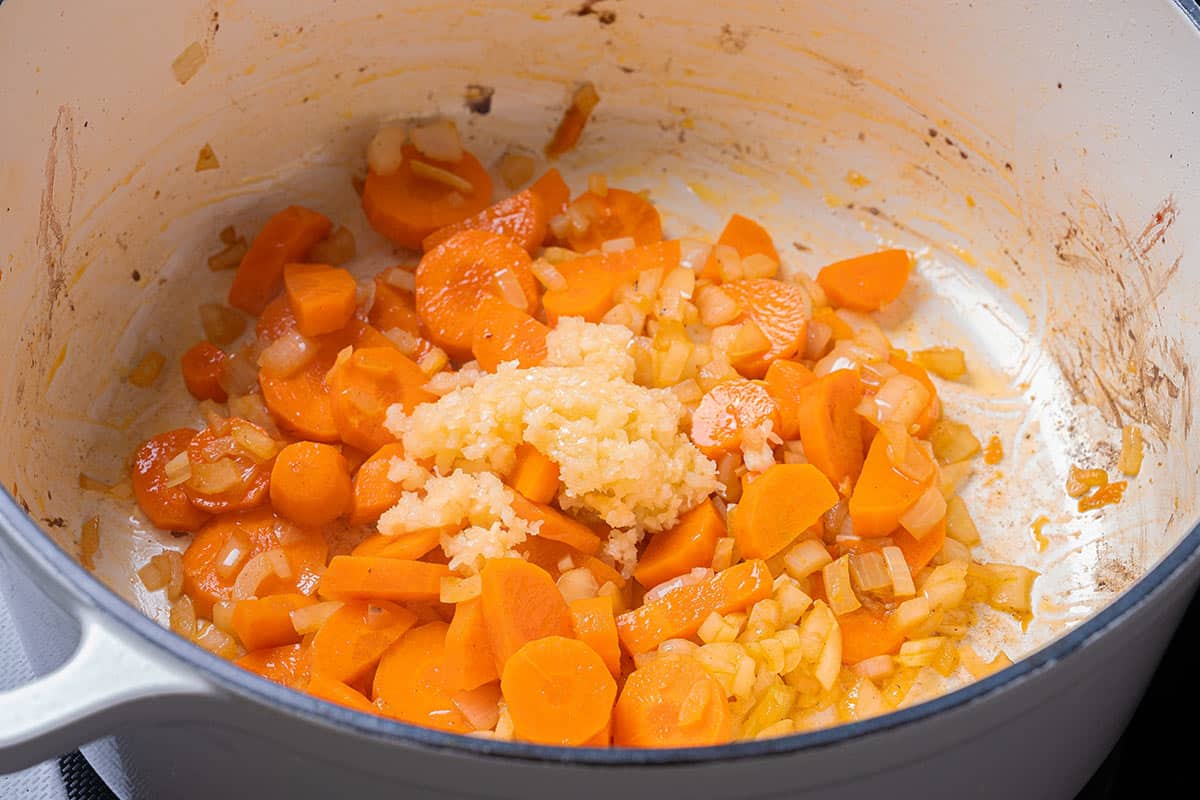carrots and diced onion sauted in a blue pot