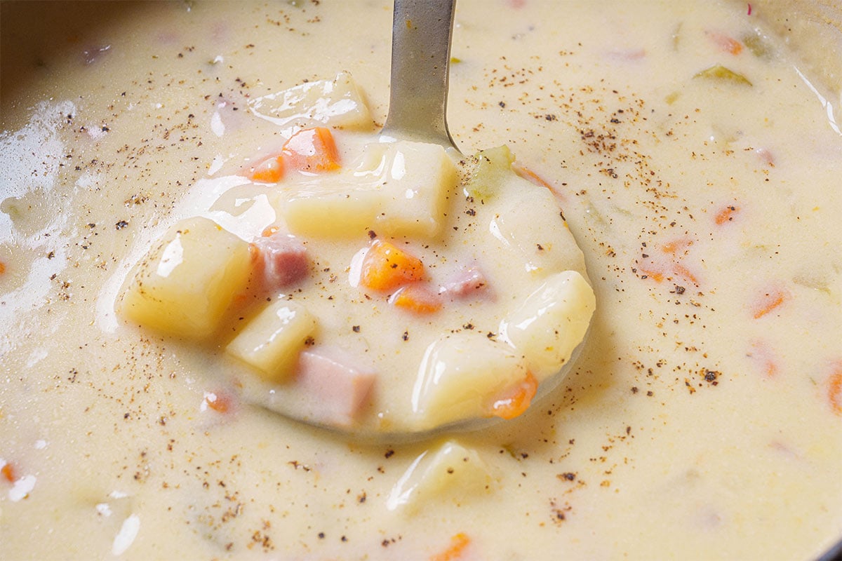 Image of the soup being removed from the oven with a spoon, ready to be plated and served.