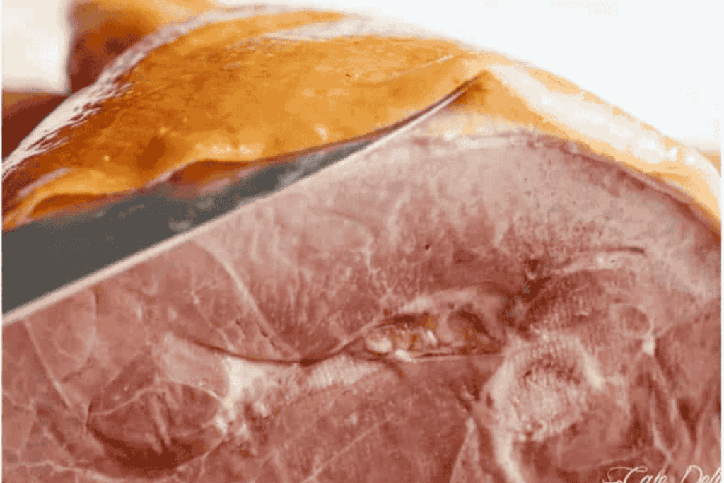 a side view showing the knife inserted under the rind but above the fat of the leg ham