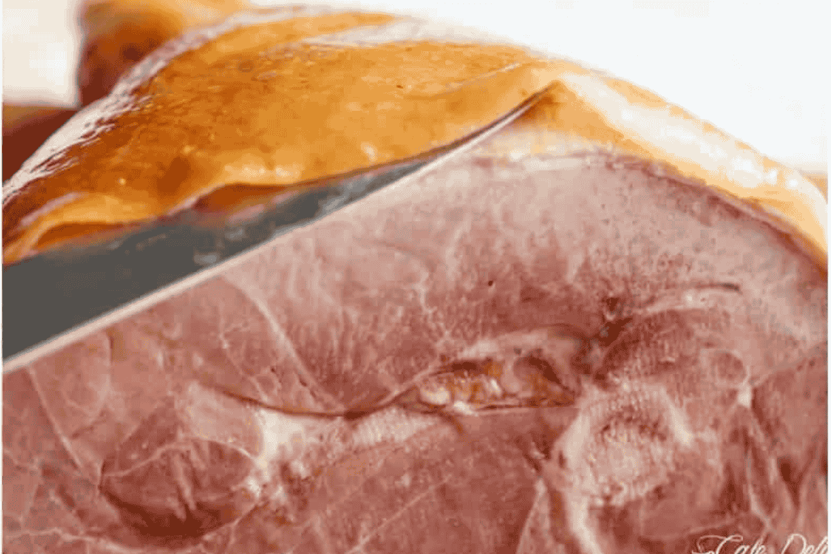 a side view showing the knife inserted under the rind but above the fat of the leg ham
