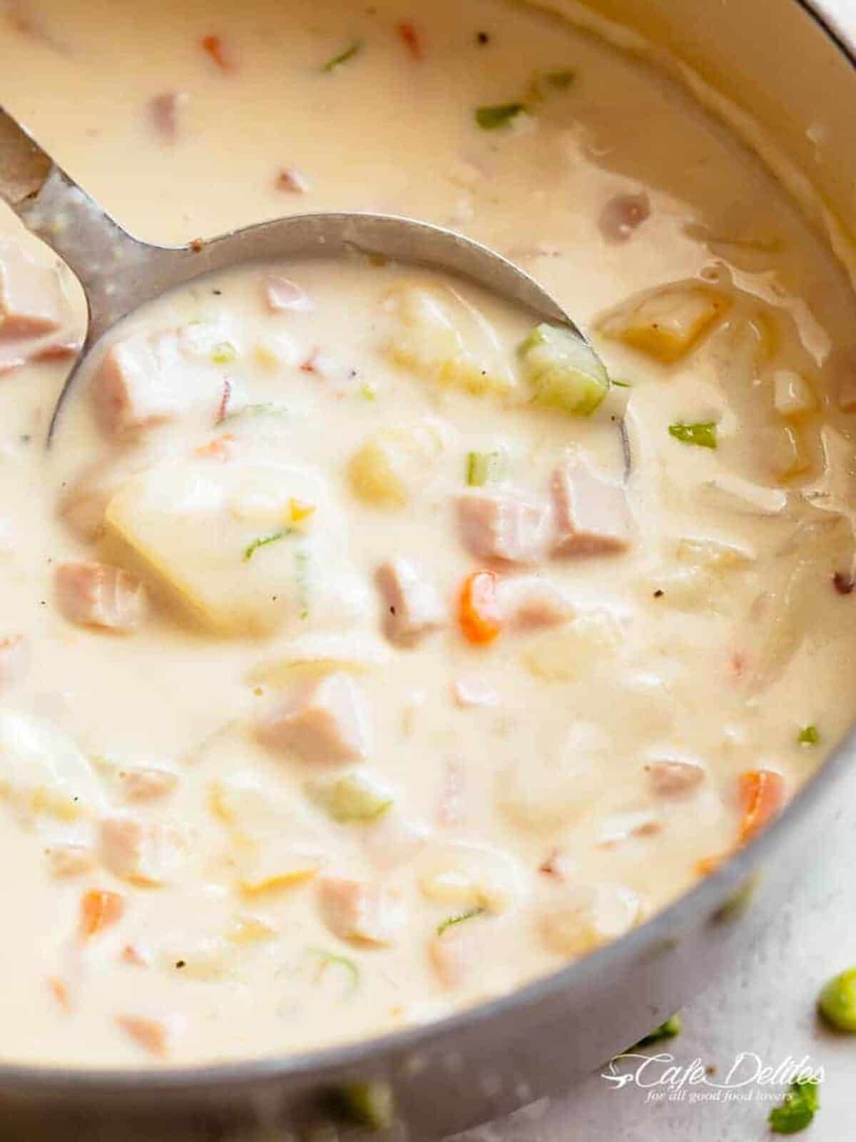 Image of creamy ham and potato soup being scooped up by a spoon, ready to be enjoyed.