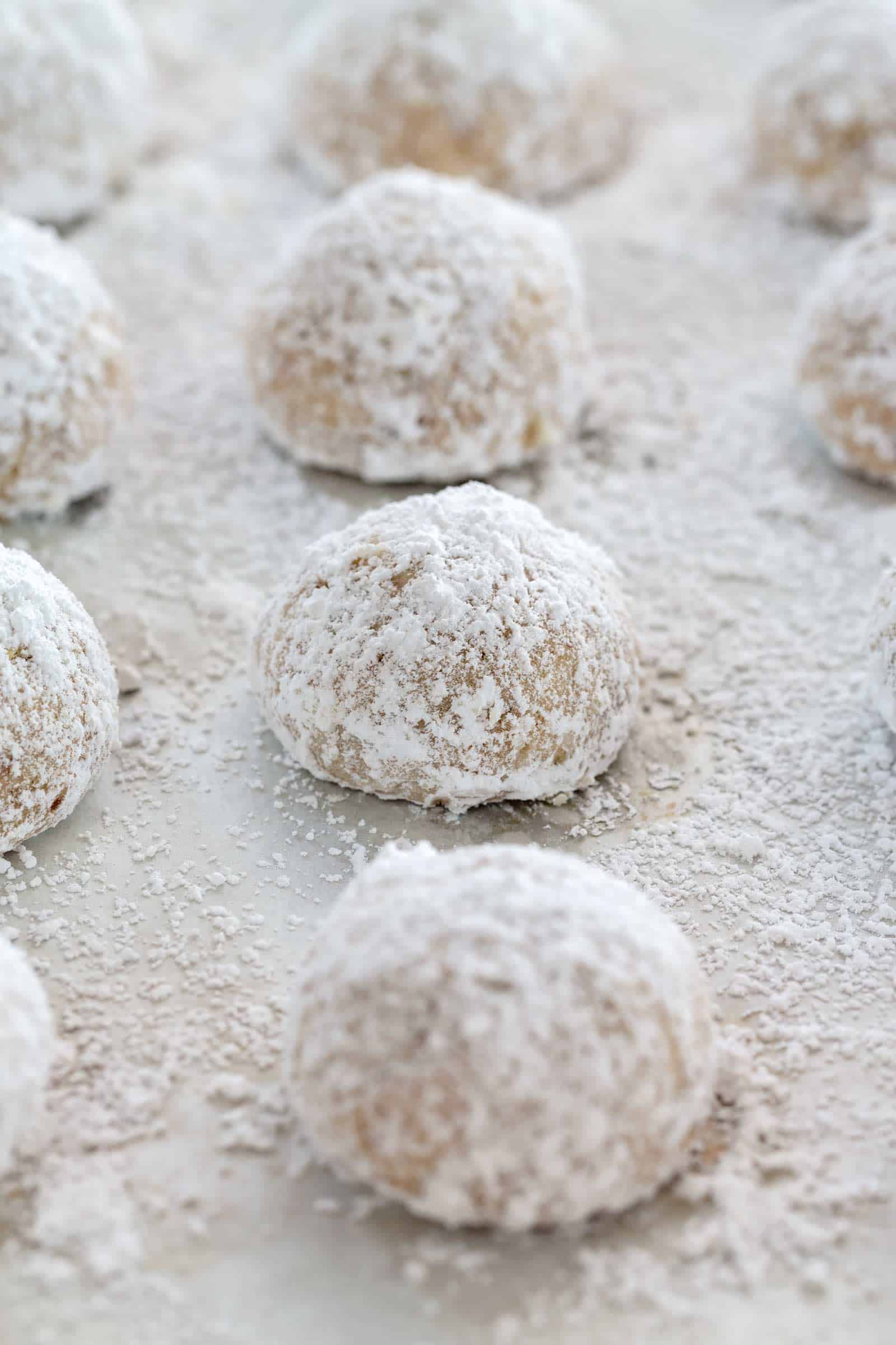 snowball cookies lined up on a baking sheet