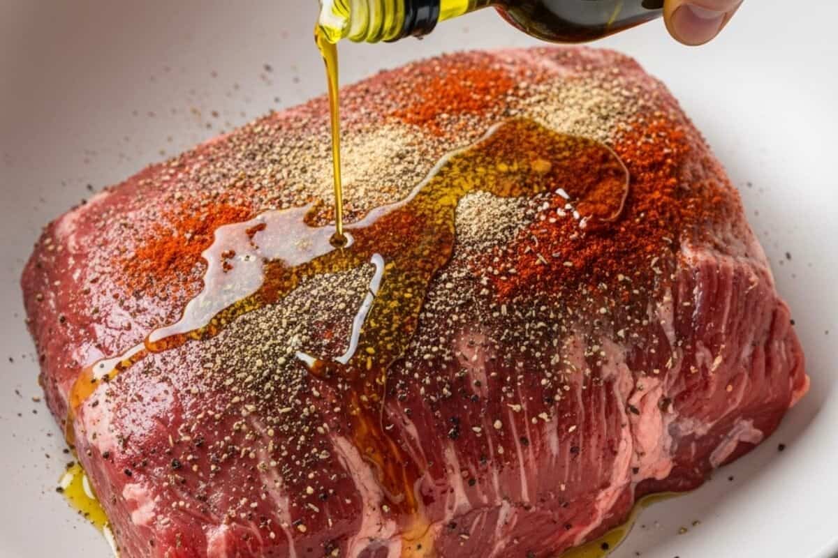 Drizzle the beef brisket with olive oil, then rub the seasoning all over the meat.
